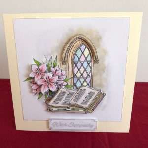 Image of card standing of church window with bible and flowers