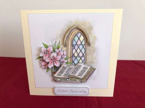 Image of card standing of church window with bible and flowers