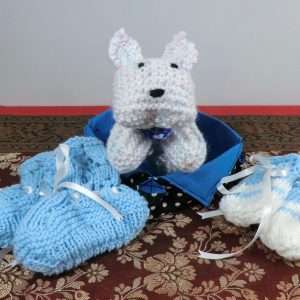 Gift box for a new baby. Box handmade from fabric, knitted bootties and mittens and a toy dog