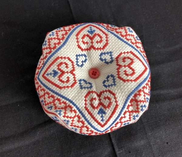 Biscornu pincushion in red and blue with heart shapes in pattern