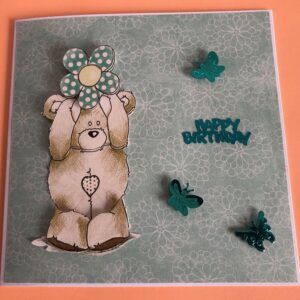 Birthday card with a teddy holding a flower with butterflies around