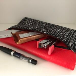front pocket of notebook showing contents, stapler, pen, ruler and snack bar