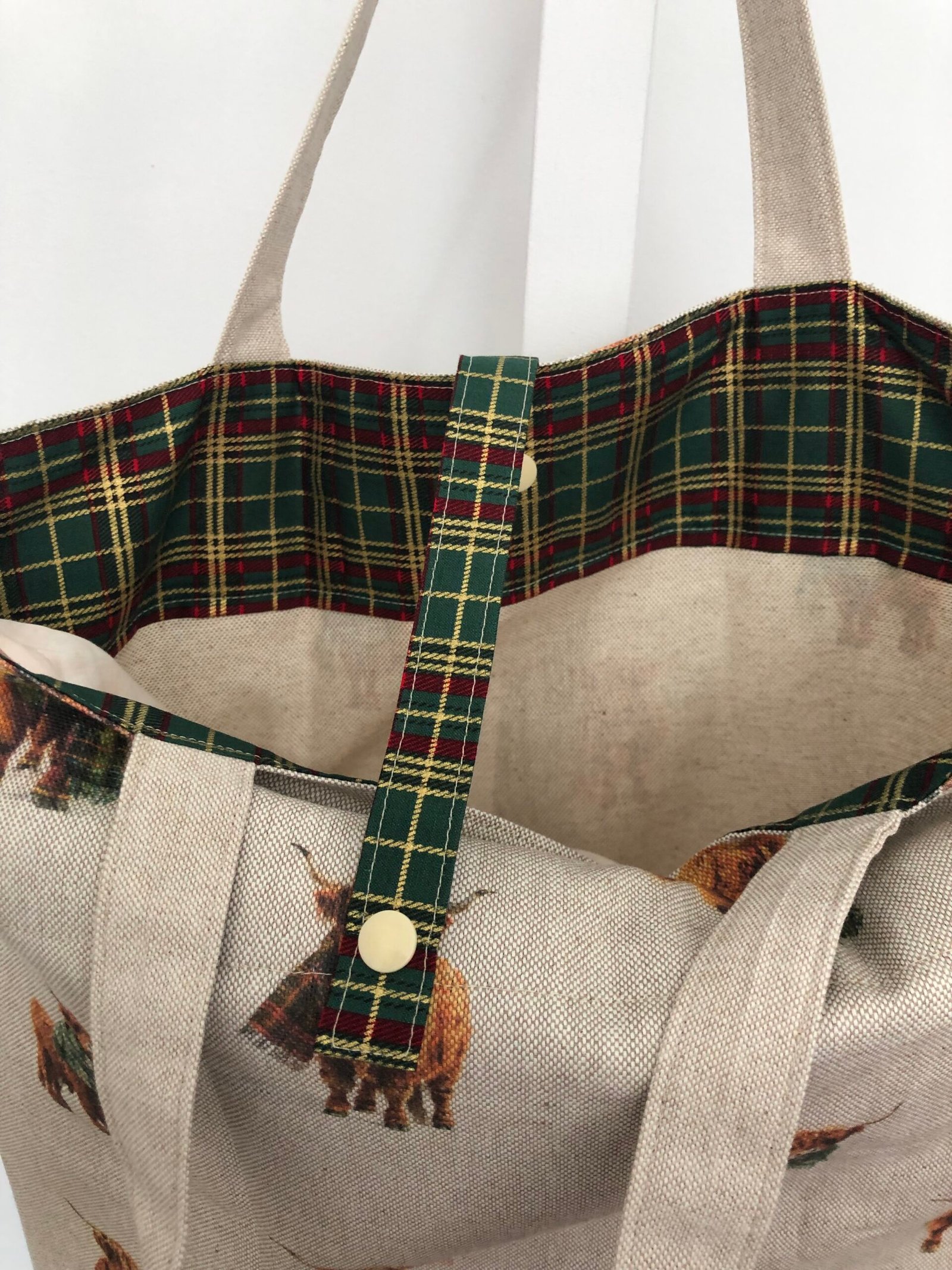Folding bag showing inside tartan accent and closing strap